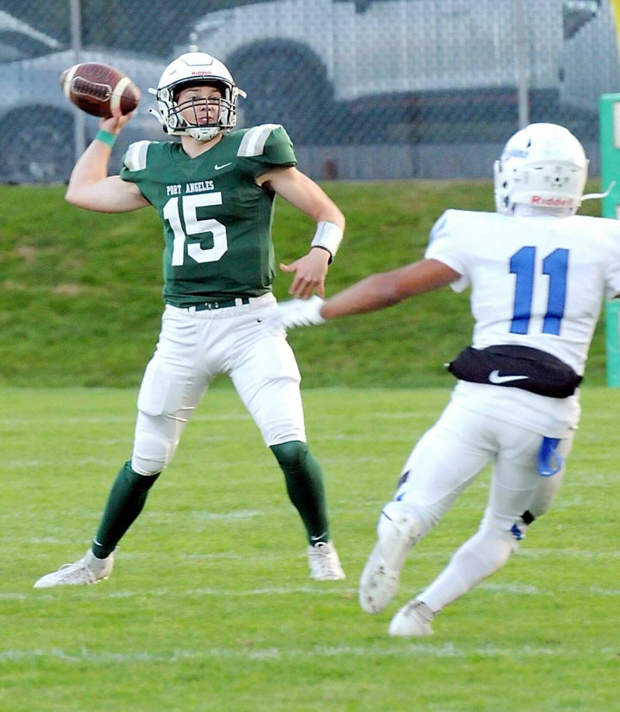 KEITH THORPE/PENINSULA DAILY NEWS Port Angeles quarterback Parker Nickerson looks to pass as Olympics Malachi Hampton closes in on Friday evening in Port Angeles.
