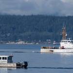 A U.S. Coast Guard boat and Kitsap County Sheriff boat search an area Sept. 5, 2022, near Freeland on Whidbey Island north of Seattle where a chartered floatplane crashed the day before, killing 10 people. On Thursday the National Transportation Safety Board confirmed that a mechanical issue caused the seaplane to crash. (AP Photo/Stephen Brashear)