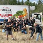 Quilcene Food Bank volunteers look on as Todd Nickerson, left, Ann Kittredge, center, and Leslie Tippins, right, break ground for a new Quilcene Food Bank at 161 Herbert St. in downtown Quilcene. (Keith Neyer)