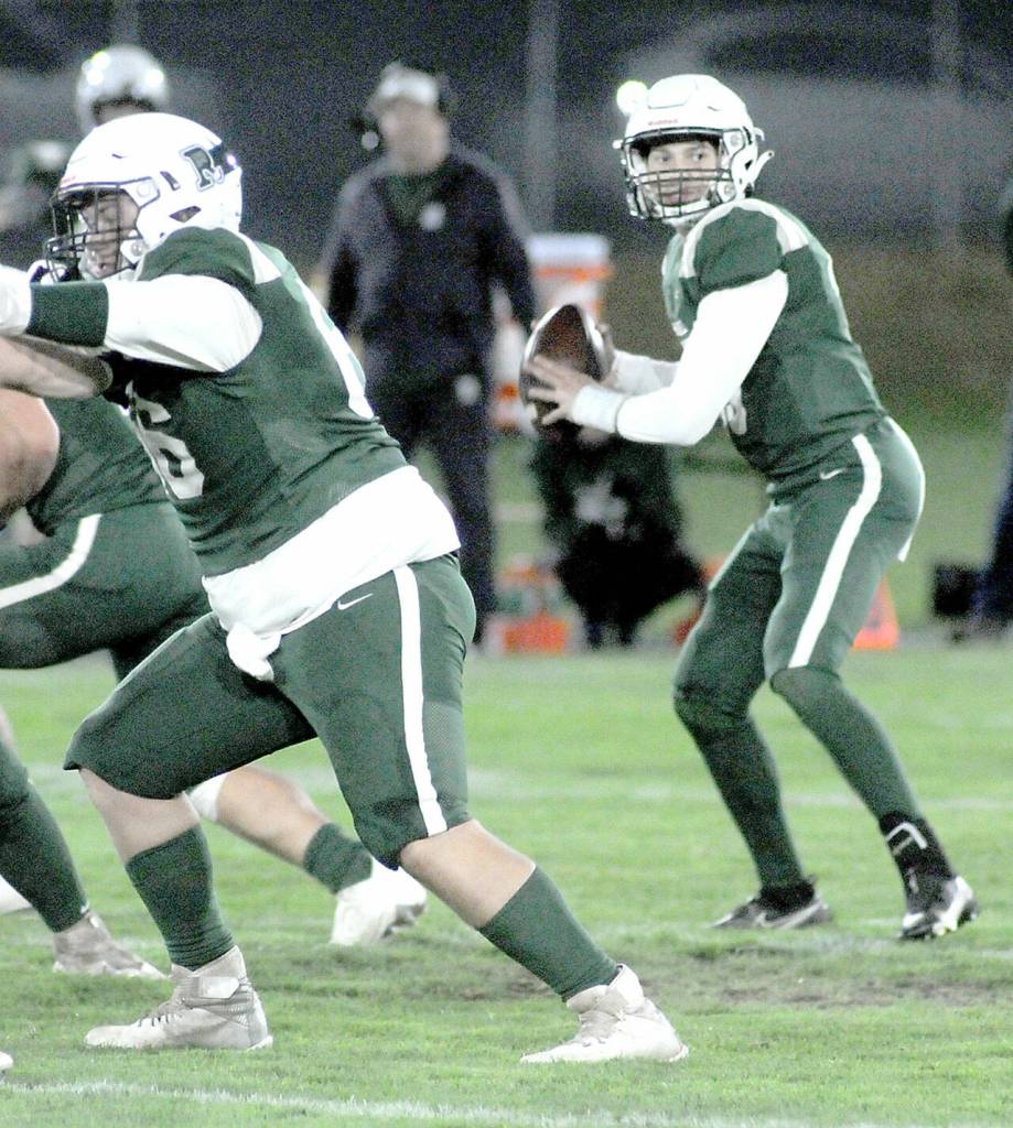 Port Angeles quarterback Parker Nickerson, right, looks to pass while receiving a block by teammate Coner Martin, left, during Fridays game against Bainbridge at Port Angeles Civic Field. (Keith Thorpe/Peninsula Daily News)