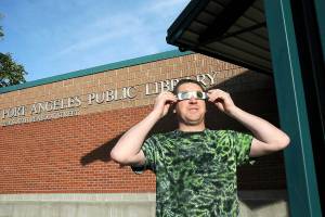 Jeff Clark, facilities technician for the North Olympic Library System, wears special glasses to observe Saturdays partial eclipse of the sun in front of the Port Angeles Public Library. The annular eclipse was visible as a ring of fire for a swath of watchers across Oregon to Texas and Mexico, was visible on the North Olympic Peninsula at about 80 percent with a large portion of the solar disc obscured by the Moon. (Keith Thorpe/Peninsula Daily News)