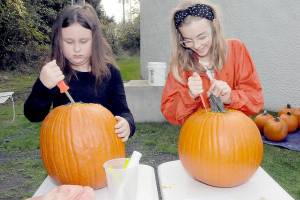 Armed with matching knives, Emma Briggance, 10, left, and Layla Newlon, 12, both of Port Angeles, prepare pumpkins for decorating during a pumpkin carving workshop on Saturday at the Port Angeles Fine Arts Center. Jack-o-lanterns created during the session were to be displayed in a pumpkin walk in the nearby Websters Woods Sculpture Park. (Keith Thorpe/Peninsula Daily News)