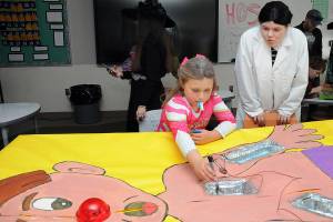 Sonnie Fountain, 8, of Sequim plays an oversized version of the Operation game under the direction of Sequim High School freshman Lillian Anderson during Saturdays Haunted Hallways holiday event at the school. Haunted Hallways featured a portion of the school set aside for a variety of Halloween games and attractions hosted by students as a benefit for the Sequim Food Bank. (Keith Thorpe/Peninsula Daily News)