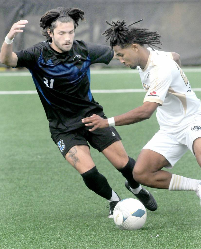 Peninsulas Abdurahim Leigh, front, dribbles past Clarks Isiah Bunda during Saturdays NWAC quarterfinal match at Wally Sigmar Field. (Keith Thorpe/Peninsula Daily News)