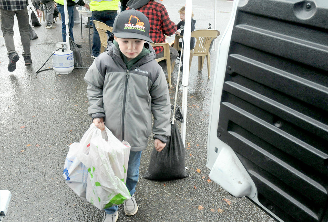 Brayden Shillington, 5, of Port Angeles carries a bag of donated food to a waiting van during Saturdays Food Drive conducted by employees of Lakeside Industries in the parking lot of Swains General Store in Port Angeles. By mid-afternoon, the participants had collected about 1,200 pounds of food and about $3,400 in monetary and matching donations to benefit area food banks. (Keith Thorpe/Peninsula Daily News)