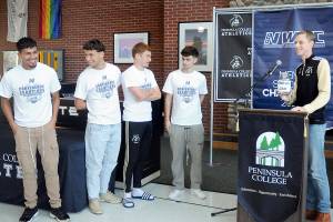Peninsula College mens soccer coach Jake Hughes, right, holds a gag swear jar poking fun of player Nil Grau, who used a number of swear words during an exuberant live-streamed postgame interview on Sunday after the team defeated Highline in the NWAC championship match on Sunday in Tukwila. The team was honored by the school at the Pirate Union Building on Tuesday. Next to the podium are players, from left, Manny Garcia, Konrad Muller, Pip van der Ende and Alfie Tucker. (Keith Thorpe/Peninsula Daily News)