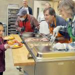 Anna-Marie Tax, 7, of Port Angeles and her brother A.J. Tax, 4, behind, are served by volunteers, from left, Phil Becillis, Lorenz Sololmann and Patty Sollman during Thursdays Community Dinner at Queen of Angeles community hall in Port Angeles. Hundreds of people took part in the free meal, which featured traditional Thanksgiving fare, dessert and the companionship of other community members. (Keith Thorpe/Peninsula Daily News)