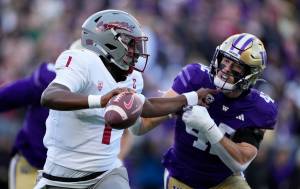 Washington State quarterback Cameron Ward blocks Washington linebacker Carson Bruener as he runs with the ball during the first half of an NCAA college football game, Saturday, Nov. 25, 2023, in Seattle. (AP Photo/Lindsey Wasson)