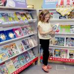 Accasia Anderson, 7, a second-grade student at Greywolf School in Sequim, examines a book for sale on Saturday at the schools Holiday Bazaar. The event, hosted by the Sequim Elementary Parent Teacher Association, spotlighted the work of more than 50 vendors, including crafts made by students, along with a Scholastic Book Fair. (Keith Thorpe/Peninsula Daily News)