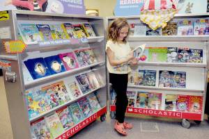Accasia Anderson, 7, a second-grade student at Greywolf School in Sequim, examines a book for sale on Saturday at the schools Holiday Bazaar. The event, hosted by the Sequim Elementary Parent Teacher Association, spotlighted the work of more than 50 vendors, including crafts made by students, along with a Scholastic Book Fair. (Keith Thorpe/Peninsula Daily News)