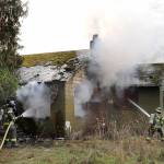 Port Angeles firefighter Ryan Gosling, left, and Samantha Harik work to extinguish a blaze at an unoccupied house at 1338 W. Lauridsen Blvd. on the edge of Port Angeles on Saturday. (Keith Thorpe/Peninsula Daily News)