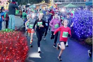 Eleanor Jones, 11, of Sequim (No. 112) leads the pack at the beginning of the Run the Peninsulas Jamestown Glow Run in Blyn late Saturday afternoon. Jones won the womens 5K as more than 450 runners participated. (Dave Logan/for Peninsula Daily News)