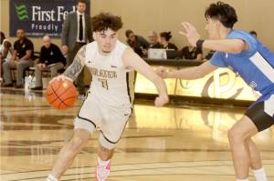 Peninsula Colleges Aiden Olmstead drives against the defense of South Puget Sound as Peninsula head coach Bryce Jacobson, background, watches the play. (Dave Logan/for Peninsula Daily News)