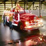 Tyler Gage and Adam DeFilippo decorate the 1956 Seagrave fire engine in 2022. (Dave Logan/For Peninsula Daily News)