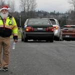 Butch Zaharias, a captain and division chief with the Community Emergency Response Team (CERT), checks in on drivers and fellow CERT members in festive garb during the Family Holiday Meal Bag distribution in Sequims Carrie Blake Park. (Matthew Nash/Olympic Peninsula News Group)