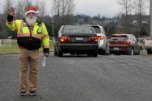 Butch Zaharias, a captain and division chief with the Community Emergency Response Team (CERT), checks in on drivers and fellow CERT members in festive garb during the Family Holiday Meal Bag distribution in Sequims Carrie Blake Park. (Matthew Nash/Olympic Peninsula News Group)