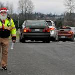 Butch Zaharias, a captain and division chief with the Community Emergency Response Team (CERT), checks in on drivers and fellow CERT members in festive garb during the Family Holiday Meal Bag distribution in Sequims Carrie Blake Park. (Matthew Nash/Olympic Peninsula News Group)