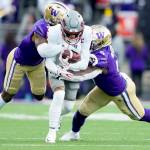 Washington State wide receiver Lincoln Victor (5) is tackled by Washington cornerback Dominique Hampton, left, and linebacker Edefuan Ulofoshio, right, during the Apple Cup on Nov. 25 in Seattle. Washington and Washington State will continue to play each other in football for at least another five years, but the Apple Cup will no longer be a conference game. (Lindsey Wasson/The Associated Press)