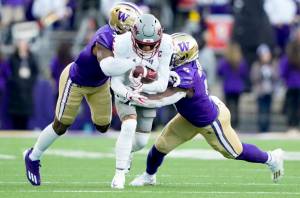 Washington State wide receiver Lincoln Victor (5) is tackled by Washington cornerback Dominique Hampton, left, and linebacker Edefuan Ulofoshio, right, during the Apple Cup on Nov. 25 in Seattle. Washington and Washington State will continue to play each other in football for at least another five years, but the Apple Cup will no longer be a conference game. (Lindsey Wasson/The Associated Press)