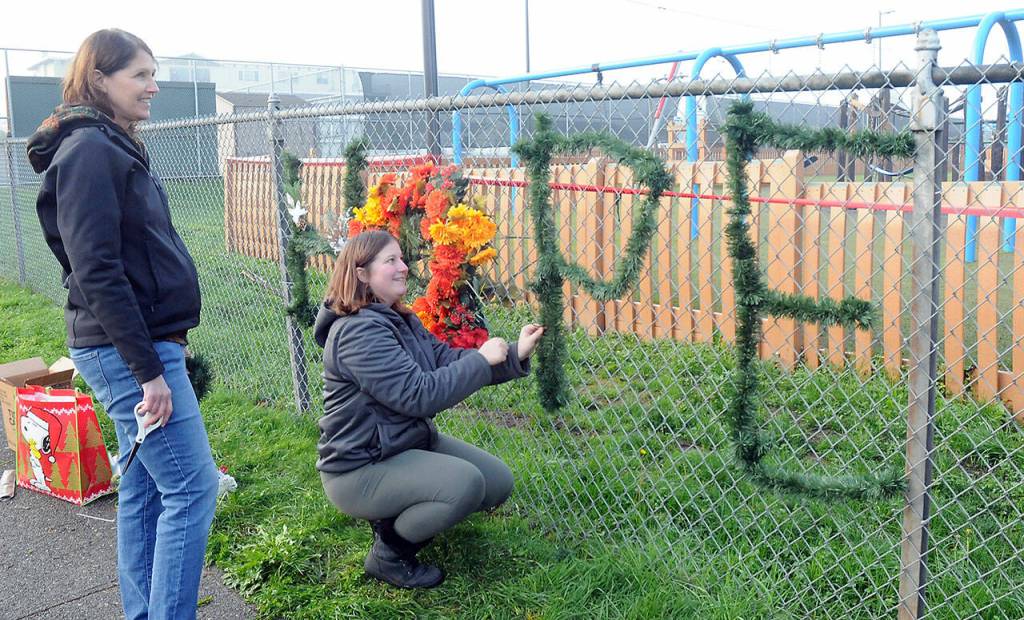 Jo Johnston, left, and Leia Kenton spell out a message of hope on the fence of Erickson Playfield after the Dream Playground was burned on Wednesday in Port Angeles. (Keith Thorpe/Peninsula Daily News)