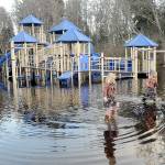 Josie Atkisson, left, and her friend, Danielle Romano, both 6 of Port Angeles, wade through a flooded area around the play equipment at Shane Park in Port Angeles on Wednesday. (Keith Thorpe/Peninsula Daily News)