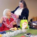 Marilyn Van Patter of Port Angeles, seated, is complimented on her decorative scarf by Capt. Crystal Birks of the Salvation Army of Port Angeles during Fridays pre-Christmas lunch at the corps facility. The meal included a clothing giveaway and gifts for participants. (KEITH THORPE/PENINSULA DAILY NEWS)