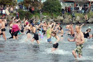 Participants in the New Years Day polar bear dip in Port Angeles run in and out of the chilly water of Port Angeles Harbor at Hollywood Beach as onlookers watch from the shore on Monday. More than 100 dippers took part in the annual ritual, which served as a fundraiser for Volunteer Hospice of Clallam County. (Keith Thorpe/Peninsula Daily News)