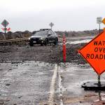 A car picks its way through a field of rocks and other debris pushed by wind-driven waves and high tides over Ediz Hook Road in Port Angeles on Tuesday. The city Public Works Department has closed the road. (Keith Thorpe/Peninsula Daily News)