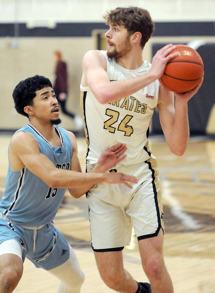 KEITH THORPE/PENINSULA DAILY NEWS Peninsulas Wyatt Dunning, a graduate of Port Angeles High School, holds off the defense of Whatcoms RaShawn Wilcox on Wednesday night at Peninsula College.