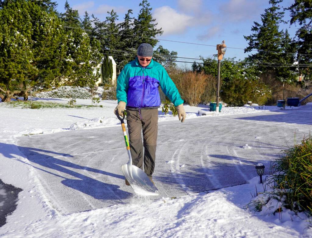Jeff Mather, from Port Townsend, finishes up shoveling about 4 inches of snow from his driveway on Friday morning after a winter storm passed through late Thursday evening. Mather moved to Port Townsend from Fiji in 2019 and is getting used to the winter conditions in the Pacific Northwest. (STEVE MULLENSKY/FOR PENINSULA DAILY NEWS)