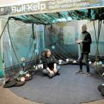 Tamara Galvan, facilities director for the Feiro Marine Life Center in Port Angeles, seated, talks about an interactive traveling bull kelp exhibit with Feiro volunteer Anni Lanigan on Thursday. (Keith Thorpe/Peninsula Daily News)
