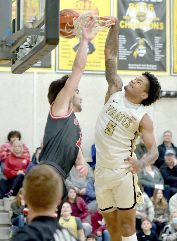 Peninsulas Javon Ervin makes the slam dunk over the head of Olympics Christian Parrish on Saturday in Port Angeles. (Keith Thorpe/Peninsula Daily News)