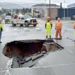 Port Angeles Public Works and Washington State Department of Transportation officials examine a sinkhole in the middle of Fifth and Lincoln streets in Port Angeles on Wednesday after water from a broken water main tore up the pavement. (Keith Thorpe/Peninsula Daily News)