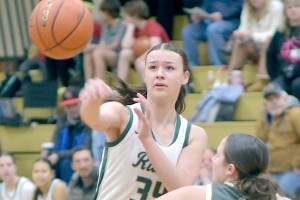 Port Angeles Lexie Smith, right, passes over the shoulder of North Kitsaps Teegan DeVries on Tuesday evening at Port Angeles High School. (Keith Thorpe/Peninsula Daily News)