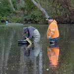 Michael Poats, left, and Brody Merritt of the Port Angeles stormwater department work to install a pump to remove standing water from a flooded area near the playground at Shane Park in Port Angeles on Wednesday. The pool of standing water, which is up to 3 feet deep in places and has at times covered the nearby play equipment, is to be pumped to a nearby storm drain. (Keith Thorpe/Peninsula Daily News)