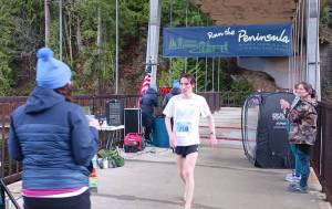 Mens 5K winner Langdon Larson of Port Angeles crosses the finish line at the Elwha Bridge Run held Saturday morning. (Pierre LaBossiere/Peninsula Daily News)