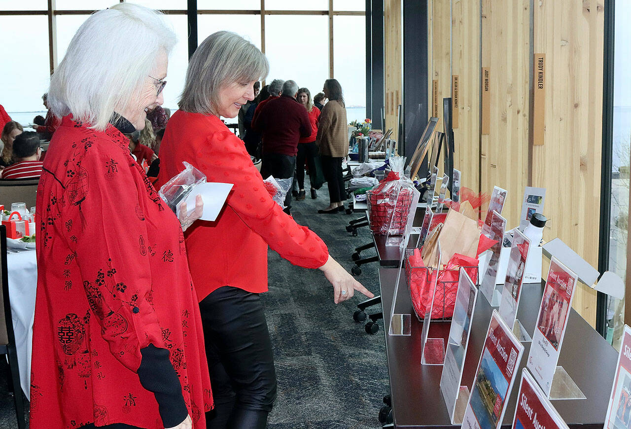 Mother and daughter Shelly Tweter and Peach Thompson look over silent auction items at the Red, Set, Go! event Friday at Field Arts & Events Hall in Port Angeles. (Dave Logan/for Peninsula Daily News)