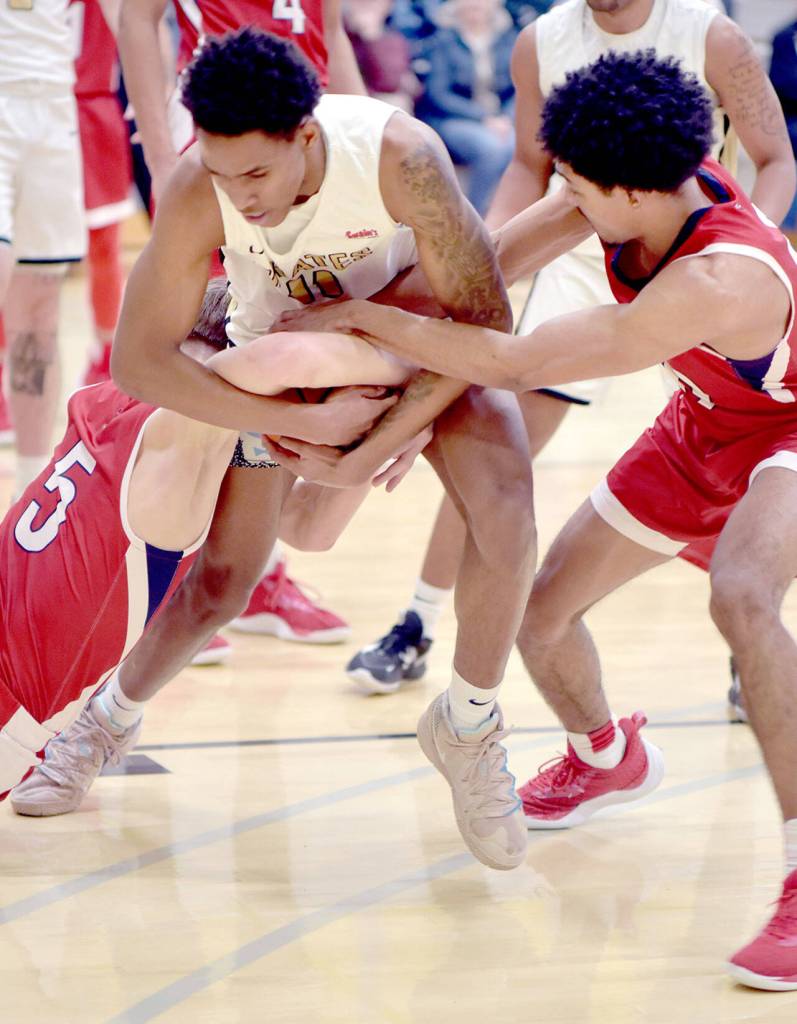 Peninsulas Antonio Odum, center, finds himself mobbed by Skagit Valleys Jacob Bilodeau, left, and Cinque Maxwell, resulting in a jump ball on Wednesday night in Port Angeles. (Keith Thorpe/Peninsula Daily News)