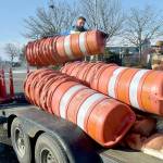 Chris Johnson of Nordland-based Nordland Construction loads traffic drums onto a trailer as coworker Robert Bufford prepares to secure the load as the pair prepares to open the parking lot at Port Angeles City Pier to automobiles on Friday. The work was part of a project to improve storm drainage, replace damaged sidewalks and ADA ramps and mitigate shoreline erosion around the lot, which had been closed since early January. Tree replacement and other project detail work is expected to follow over the next few weeks. (KEITH THORPE/PENINSULA DAILY NEWS)