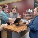 Coffee customer Lauren Wright of Port Angeles, right, gets assistance at the counter from Career and Technical Education program students, from left, Jordis Vance, 17, Rayin Blewett, 18, and Maple Romberg, 16, on Fridays opening day of the Wildcat Cafe at Lincoln Center in Port Angeles. (KEITH THORPE/PENINSULA DAILY NEWS)