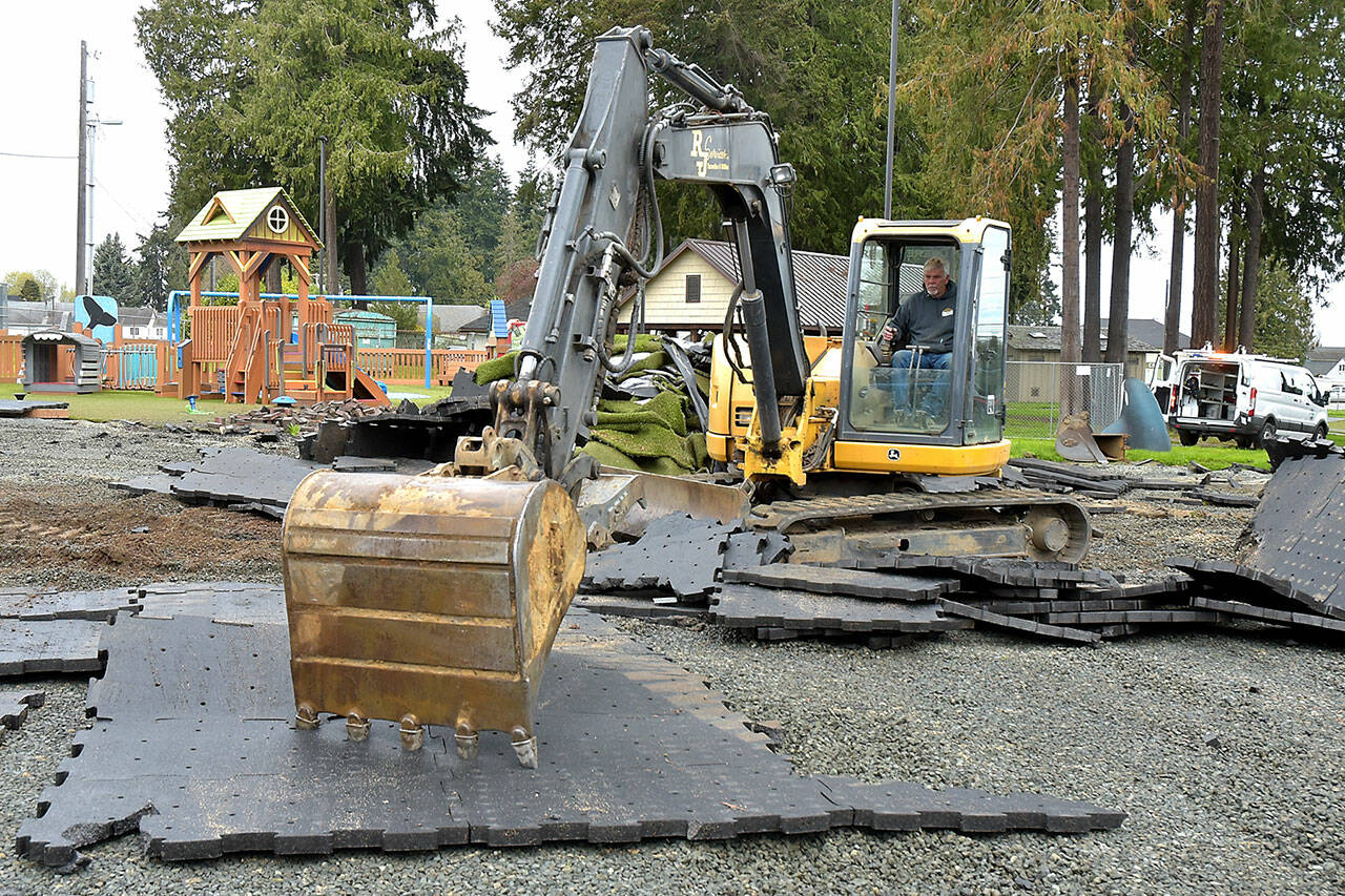 Kelly Couthlin of Port Angeles-based RJ Services Inc. uses an excavator to remove damaged surface padding tiles at the Dream Playground at Erickson Playfield in Port Angeles on Thursday. Surface removal paves the way for rebuilding the playground, currently scheduled as a volunteer community effort on May 15-19. A large portion of the playground was destroyed in an arson fire on Dec. 20. (Keith Thorpe/Peninsula Daily News)