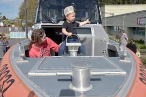Clayton Hergert, 2, along with is mother, Mandy Hergert of Port Angeles, sit at the bow of a U.S. Coast Guard response boat on display during Saturdays Healthy Kids Day at the Port Angeles YMCA. The event, hosted by all three Olympic Peninsula YMCA branches, featured childrens activities designed to promote a healthy lifestyle and a love for physical activity. (Keith Thorpe/Peninsula Daily News)