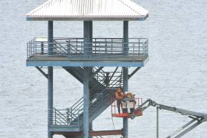 A repair crew performs work on the observation tower at the end of Port Angeles City Pier on Wednesday as part of a project to repair structural deficiencies in the tower, which has been closed to the public since November. The work, being performed by Aberdeen-based Rognlins Inc., includes replacement of bottom supports and wood decking, paint removal and repainting of the structure. Work on the $574,000 project is expected to be completed in June. (Keith Thorpe/Peninsula Daily News)