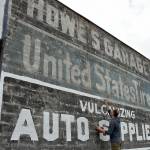Kyle Zimmerman, co-owner of The Hub at Front and Lincoln streets in downtown Port Angeles, adds a new coat of paint on Wednesday to an advertising sign on the back of his building that was uncovered during the demolition of a derelict building that once hid the sign from view. Zimmerman said The Hub, formerly Mathews Glass and Howe's Garage before that, is being converted to an artist's workspace and entertainment venue with an opening set for late May or early June. Although The Hub will have no control over any new construction that might later hide the automotive signs, Zimmerman said restoring the paint is an interesting addition to the downtown area for as long as it lasts. (Keith Thorpe/Peninsula Daily News)