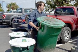 Benji Astrachan of Sisterland Farms collects bins of unwanted food collected by restaurants at the Wharf in Port Angeles. (Keith Thorpe/Peninsula Daily News)
