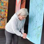 Port Townsend artist Sue Gale hangs one of the 16-inch by 60-inch banners now on display at the Peninsula Fiber Artists Fiber Habit walk-by exhibit at 675 Tyler St. in Port Townsend. Most pieces in the exhibit are available for purchase directly from the artists.