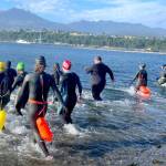 Competitors in the second annual Orca Bait Swim enter Port Angeles Harbor on Sunday for the 1.5-mile race from the Sail & Paddle Park on Ediz Hook to Pebble Beach Park. The start was relocated from the boat ramp near the U.S. Coast Guard station due to rough water and a large vessel anchored near the finish. All 10 swimmers  nine women and one man  completed the race. (Paula Hunt/Peninsula Daily News)