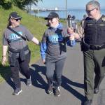 Clallam County Sheriff Brian King, right, carries a ceremonial torch with Special Olympian William Sirguy, center, accompanied by his mother, Katie Sirguy, during Fridays Special Olympics Law Enforcement Torch Run along the Waterfront Trail in Port Angeles. The event, designed to raise awareness and funds for the Special Olympics movement, brought together law enforcement officers from Clallam, Jefferson and Kitsap counties for a march across the North Olympic Peninsula. (Keith Thorpe/Peninsula Daily News)