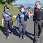 Clallam County Sheriff Brian King, right, carries a ceremonial torch with Special Olympian William Sirguy, center, accompanied by his mother, Katie Sirguy, during Fridays Special Olympics Law Enforcement Torch Run along the Waterfront Trail in Port Angeles. The event, designed to raise awareness and funds for the Special Olympics movement, brought together law enforcement officers from Clallam, Jefferson and Kitsap counties for a march across the North Olympic Peninsula. (Keith Thorpe/Peninsula Daily News)