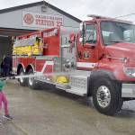 Abby Counts, 8, with assistance from her father, Taylor Counts, an EMT with Clallam 2 Fire-Rescue, gives a newly acquired tender truck a ceremonial wash down during a push-in ceremony on Saturday at the districts Station 22. The truck, tender 22, cost $459,439 and was paid for by the fire districts 2020 levy lid lift. Saturdays ceremony also included a blessing by the Lower Elwha Klallam Tribe and a push-in of the truck into its berth. The tender replaces a 31-year-old truck that had reached the end of its useful life. (Keith Thorpe/Peninsula Daily News)